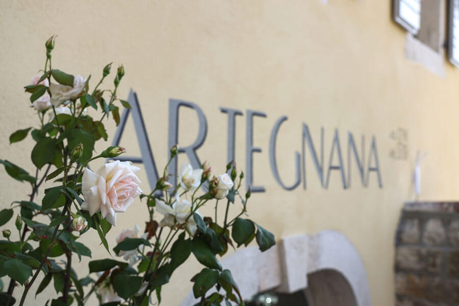 Artegnana name on the facade with blooming roses in the foreground