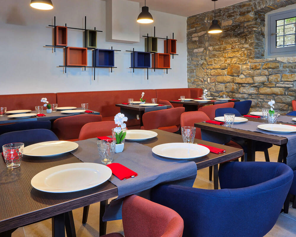 Bistro Artegnana interior with stone walls, blue velvet chairs and warm lighting