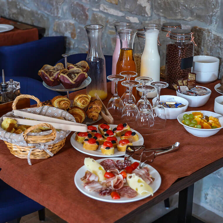 Bistro Artegnana breakfast table with croissants, prosciutto, cheese, bruschetta and fresh juices