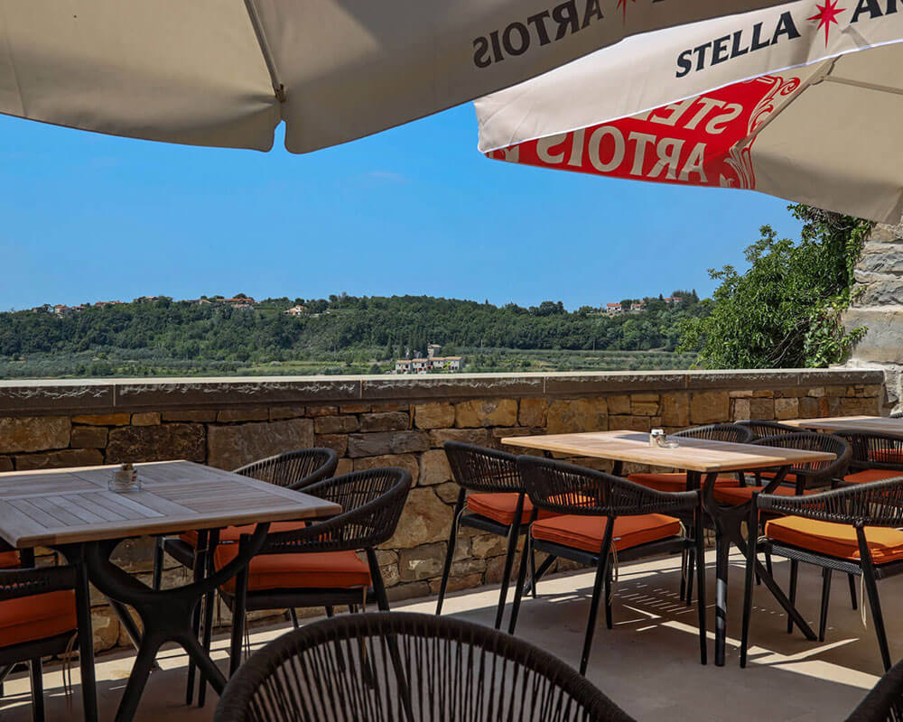 Bistro Artegnana sun-lit terrace with stone walls and panoramic countryside views