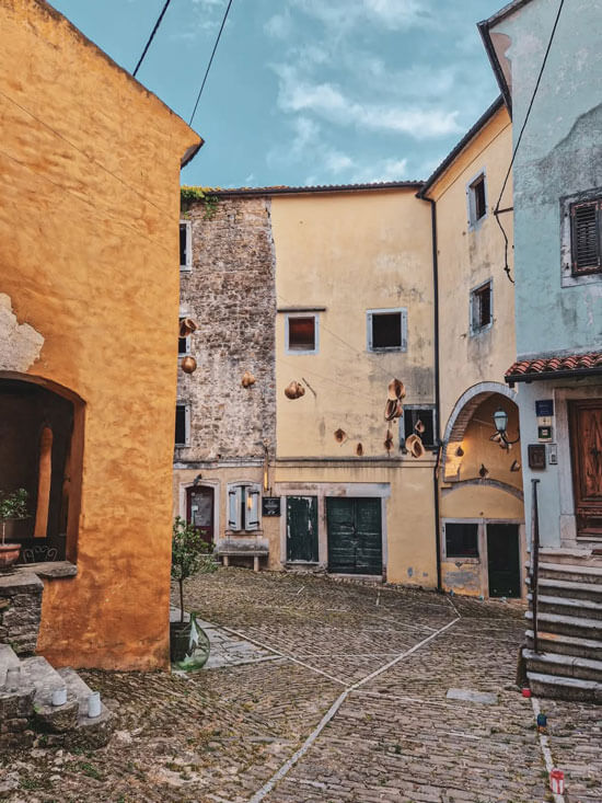 Grožnjan cobblestone square with warm-toned facades and hanging art installations