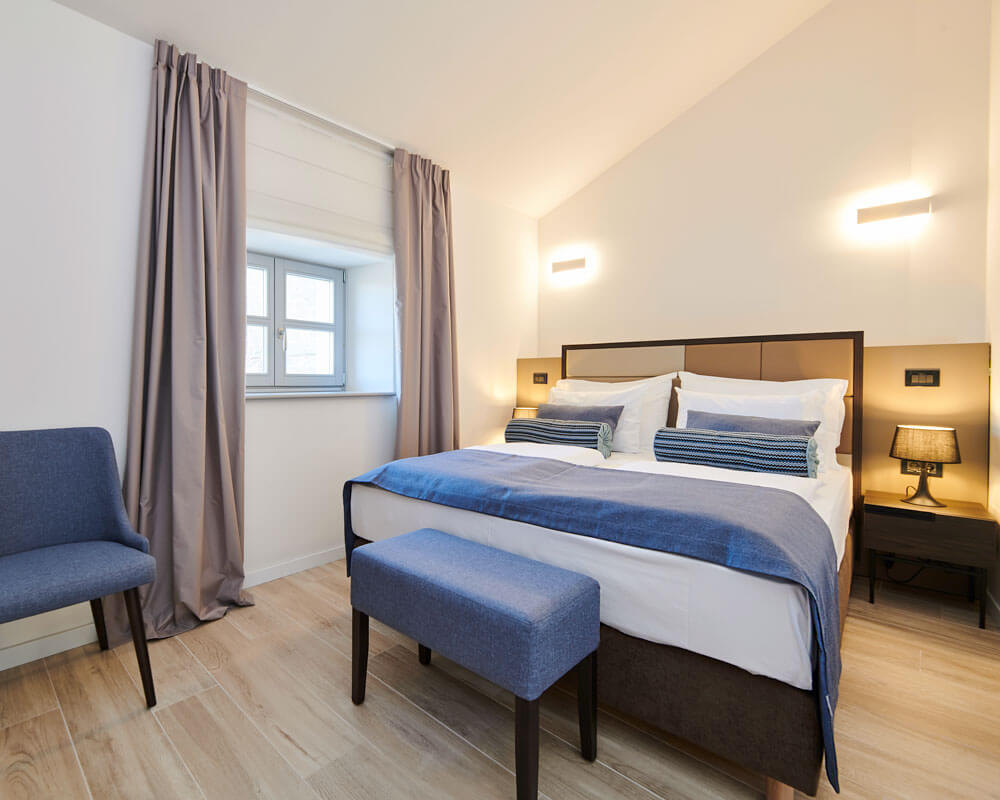 Standard Double Room with blue accents, upholstered headboard and warm lighting at B&B Artegnana 1798