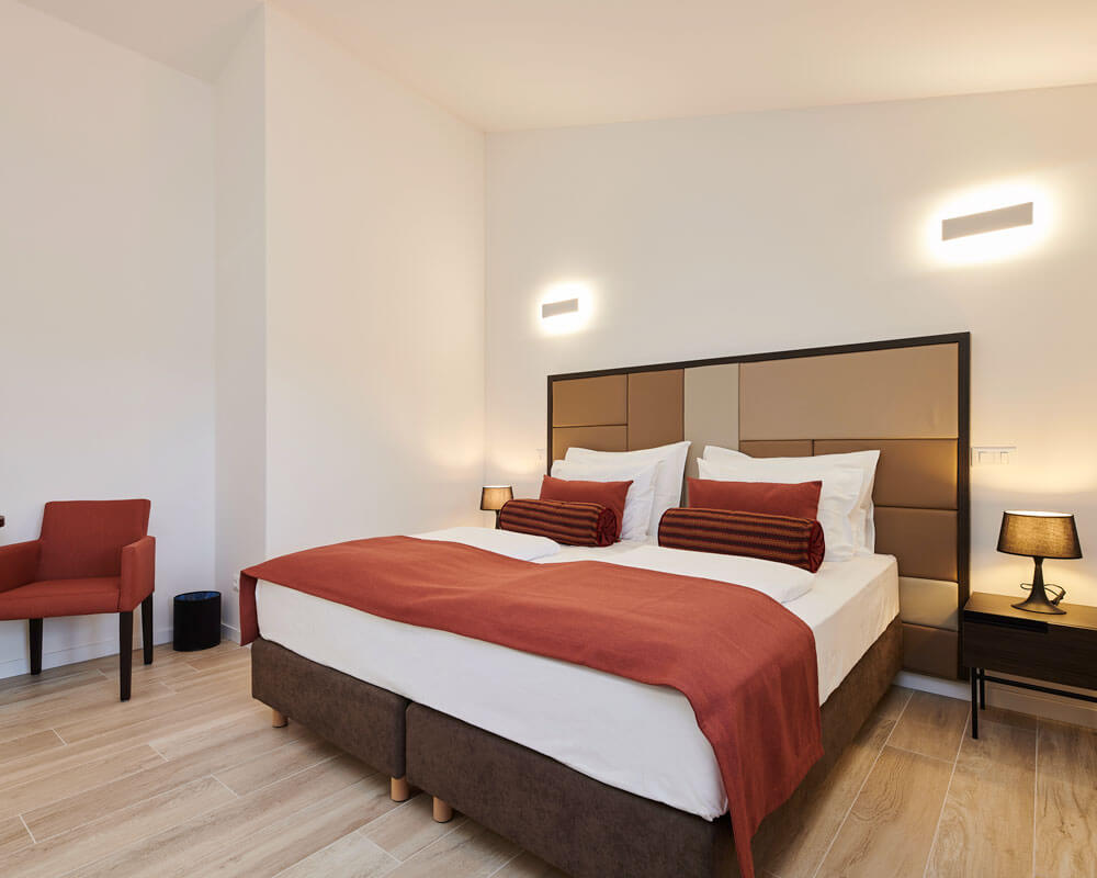 Superior Twin Room with terracotta accents, armchair and warm lighting at B&B Artegnana 1798